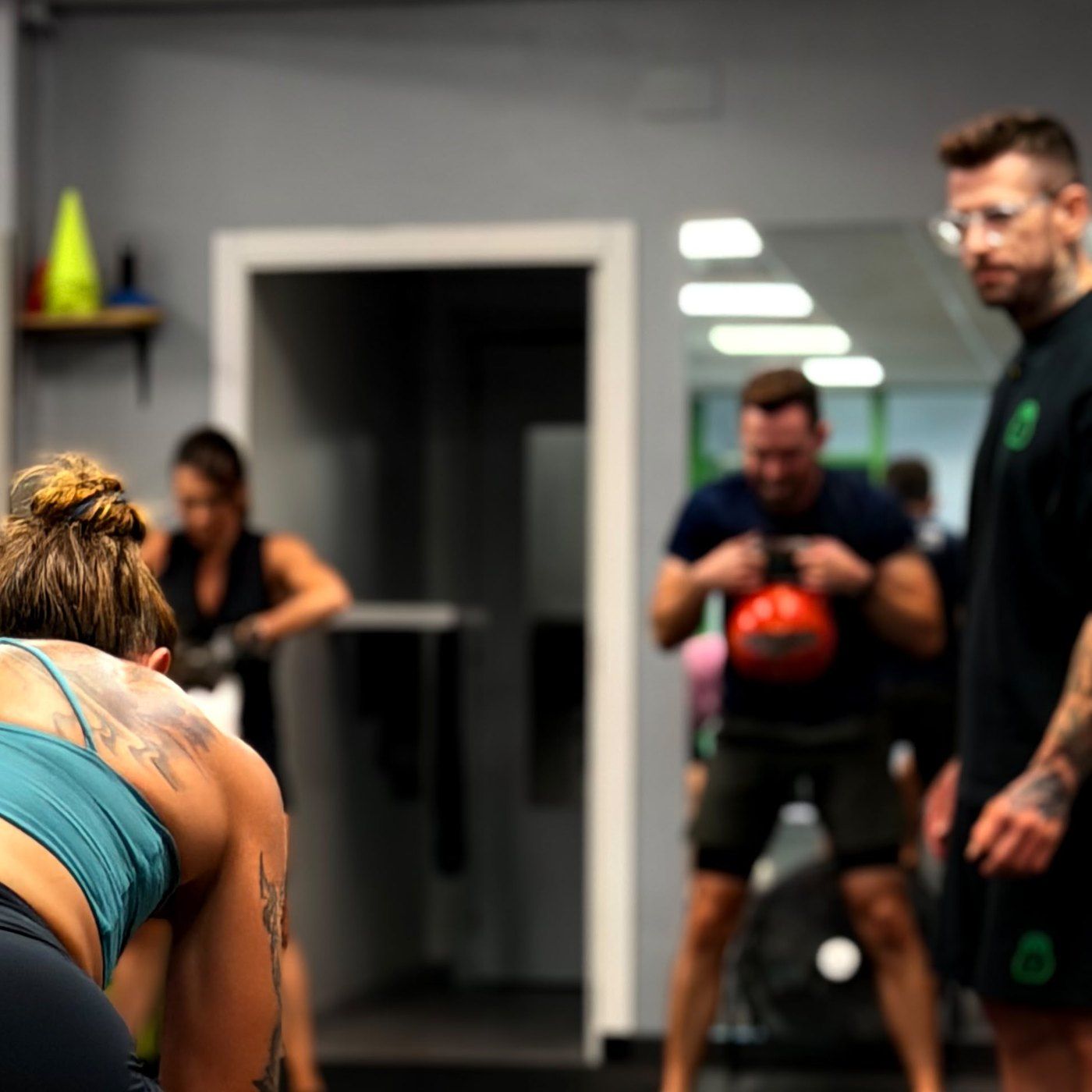 Clase en el centro de Calle Oriente: una alumna prepara un peso muerto con kettlebell mientras Carlos supervisa al grupo